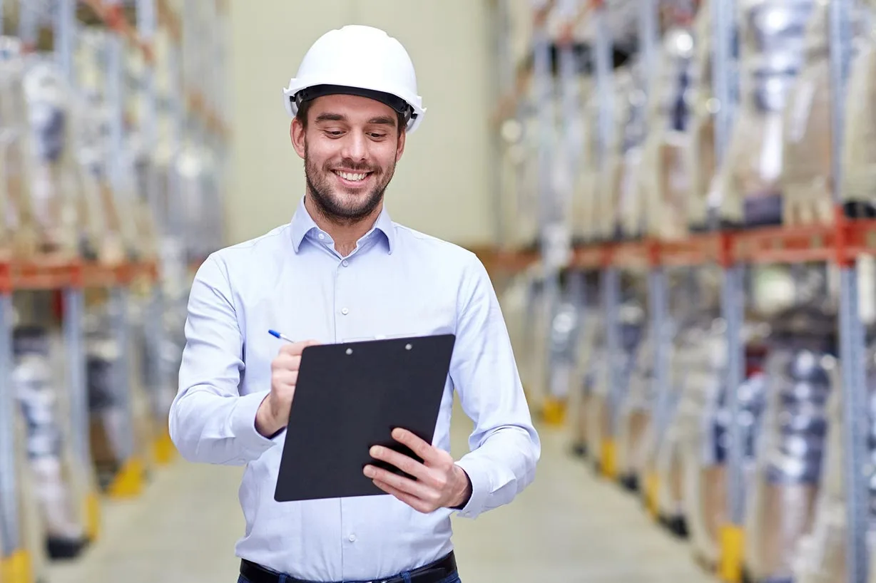 A smiling logistics manager checking stock in a warehouse